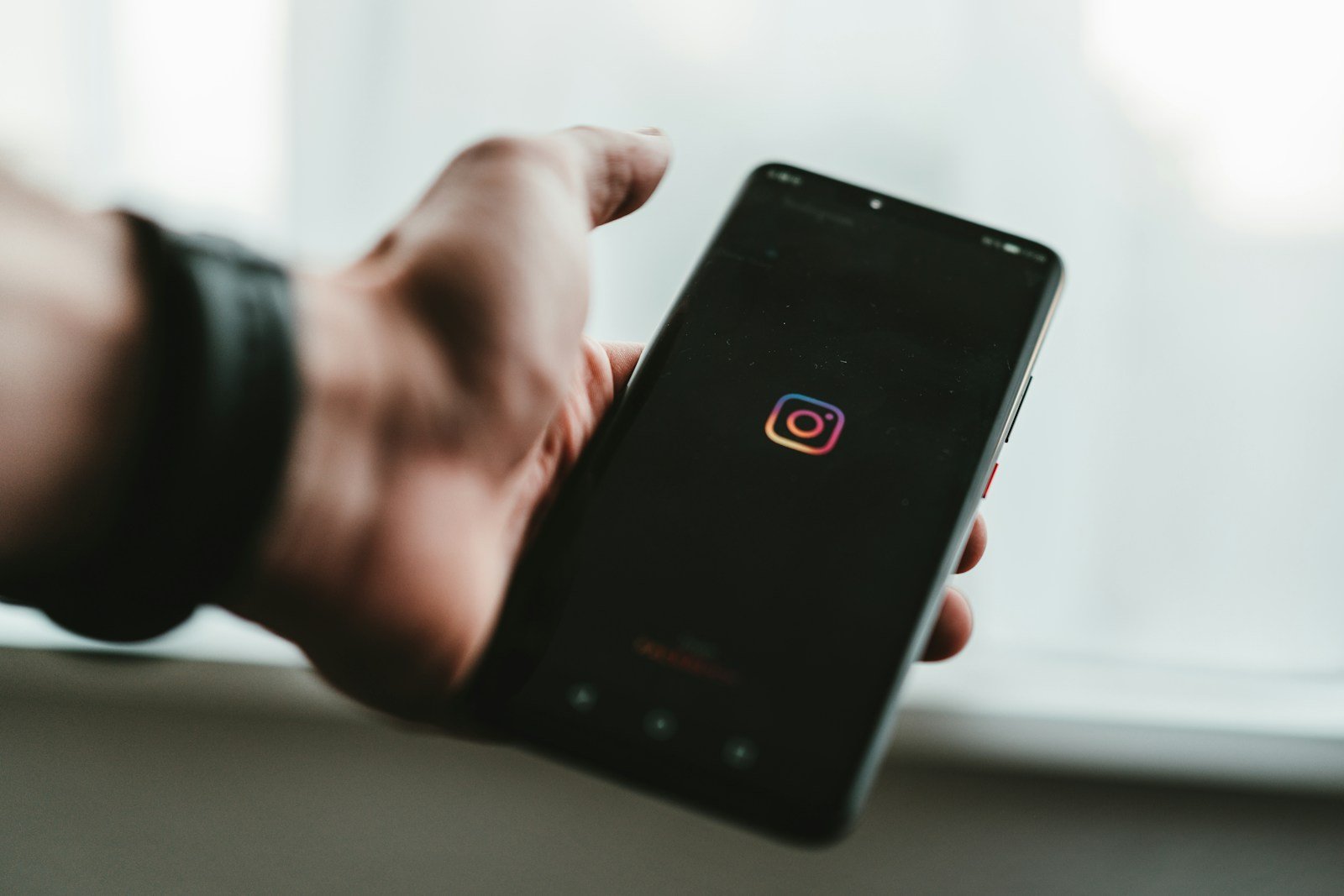 Tangan memegang ponsel yang membuka aplikasi, ilustrasi cara beriklan di Instagram untuk pemula