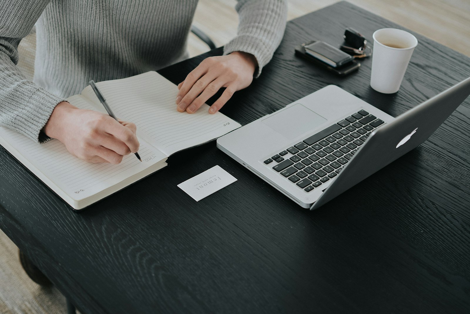 Seseorang menulis catatan di meja dengan laptop, ilustrasi cara kerja affiliate marketing