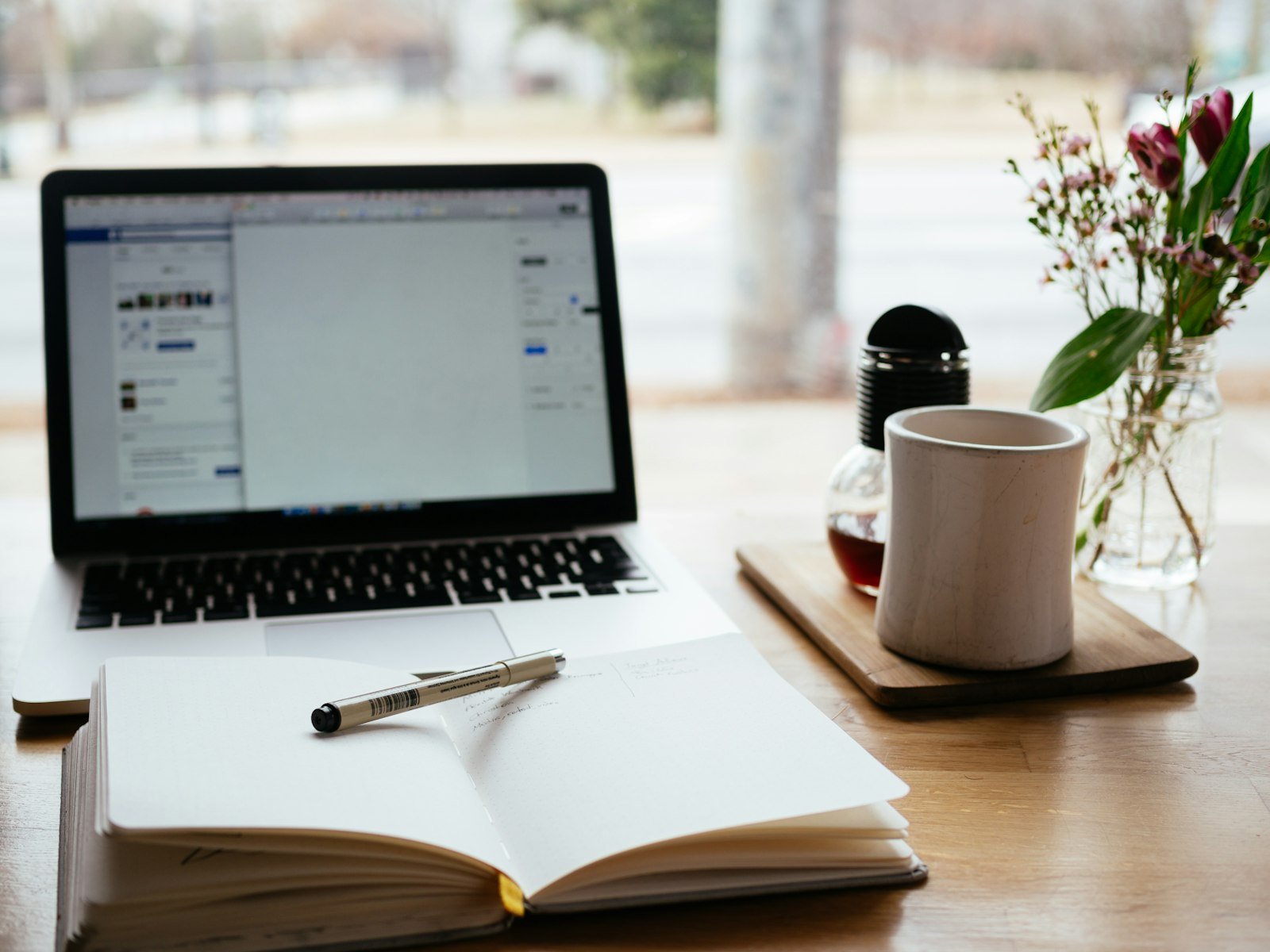 Cara riset keyword untuk bisnis jasa: laptop dan buku catatan di meja kerja