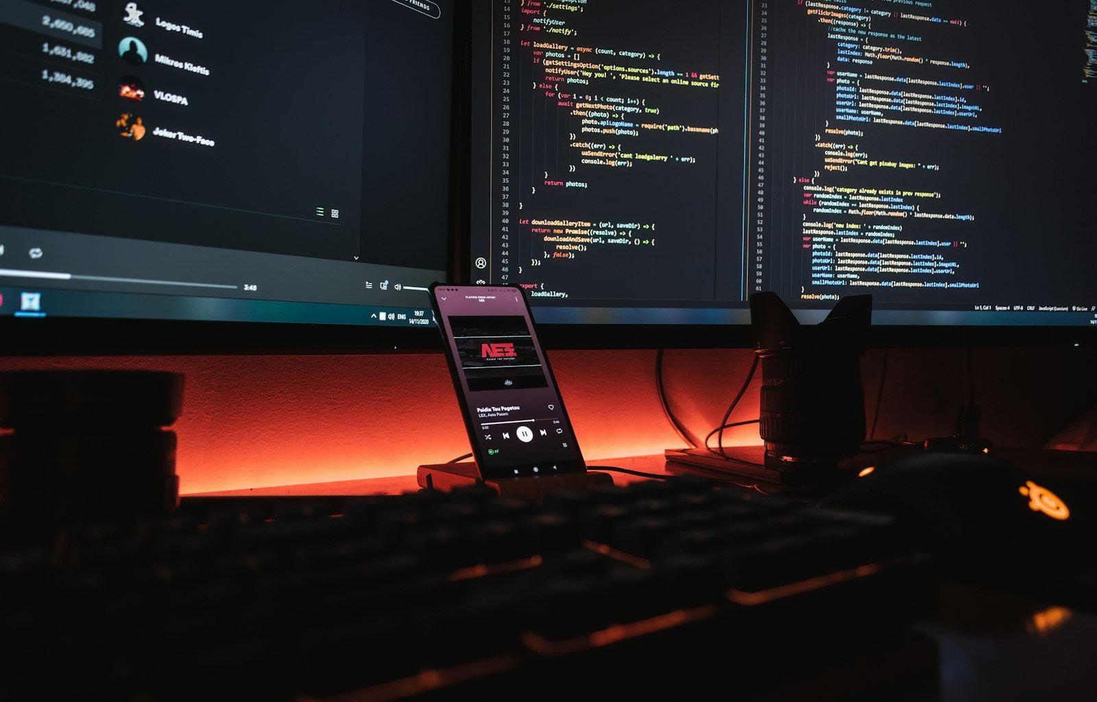 Jasa pembuatan aplikasi mobile: ponsel dan monitor berisi kode program di meja developer